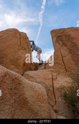 Woman climbing, hiking in Joshua Tree National Park over large boulders Stock Photo