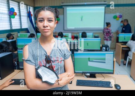 Half-length portrait of a young Latin woman from Central America in a classroom full of computers Stock Photo