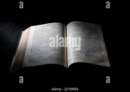 Old Bible, open book on black background, grazing light Stock Photo
