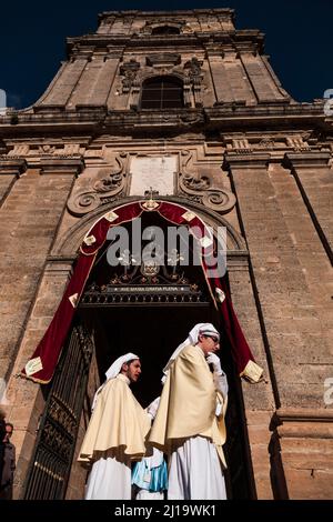Two young members of a brotherhood dressed for Good Friday at the door of the Cathedral of Enna, Sicily, Italy Stock Photo