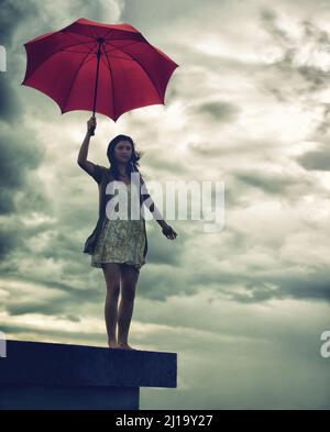 Ready to face lifes storms. Cute young woman holding an umbrella while standing on a rooftop. Stock Photo