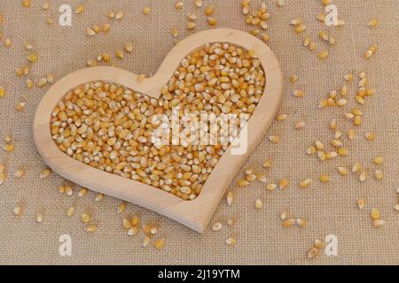 Close up shot of raw popcorn seeds In a wooden heart plate Stock Photo