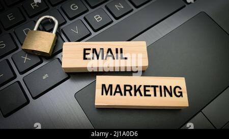 Email marketing text on wooden blocks with pad lock and laptop background. Online business concept Stock Photo