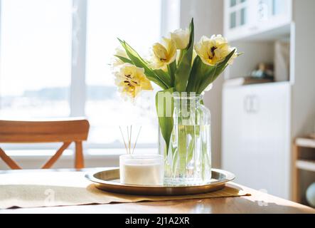 Beautiful bouquet of yellow tulips in vase on dinner table in white kitchen light interior at the home Stock Photo