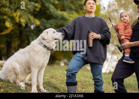 Multiracial male friends rest with dog in nature at autumn Stock Photo