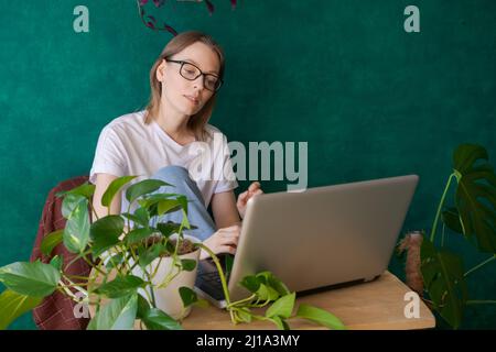 Electronic documents. Concentrated young small business woman florist owner using laptop on desktop in studio. Floral arranger designer browsing internet researching customer search trends online Stock Photo