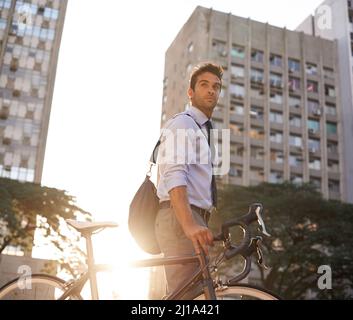 Serious about his carbon footprint as low as possible. Shot of a businessman commuting to work with his bicycle. Stock Photo