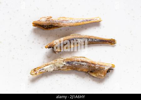 few dried anchovy fishes close up on gray plate Stock Photo