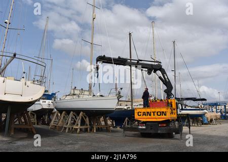 Yacht mast being removed by a crane, Almerimar marina boatyard, Almeria, Spain Stock Photo