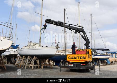 Yacht mast being removed by a crane, Almerimar marina boatyard, Almeria, Spain Stock Photo