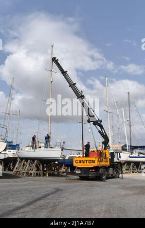 Yacht mast being removed by a crane, Almerimar marina boatyard, Almeria, Spain Stock Photo