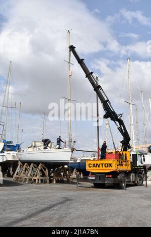 Yacht mast being removed by a crane, Almerimar marina boatyard, Almeria, Spain Stock Photo