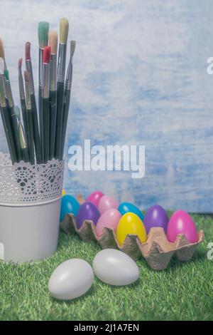 Colored Easter eggs in egg on grass with paint brushes Stock Photo