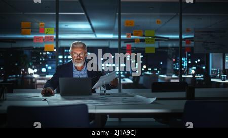 Successful Senior Businessman Working on Laptop Computer in Big City Office Late in the Evening. Investment Analyst Checking Financial Management Repo Stock Photo