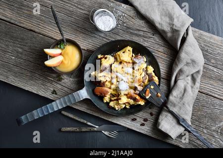 Traditional Viennese Kaiserschmarrn, shredded sweet pancakes with raisins, served in an iron frying pan on old wooden planks on a slate plate Stock Photo