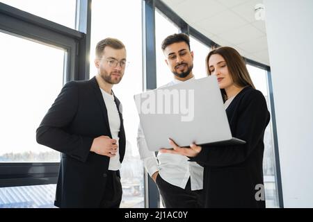 Three office workers watching a project on a laptop Stock Photo