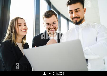 Joyful office workers looking at laptop Stock Photo