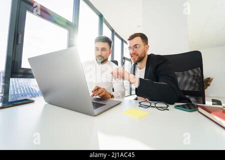 Two multiracial male office workers working on a laptop. IT company employees Stock Photo
