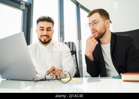 Two office workers are thinking about a new project while sitting at a laptop Stock Photo