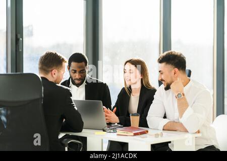 Young office workers hold business negotiations in the office sitting in front of a laptop Stock Photo