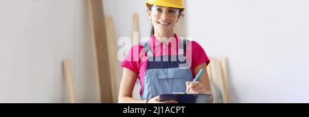 Woman builder in protective helmet holding clipboard with documents Stock Photo