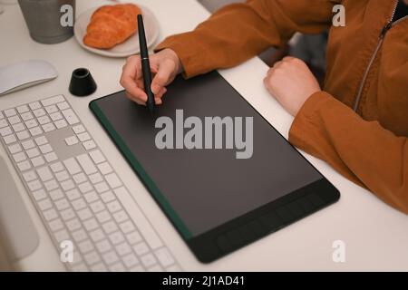 Close-up image, Female graphic designer or photo editor using graphic tablet and stylus pen at her office desk. focus hands Stock Photo
