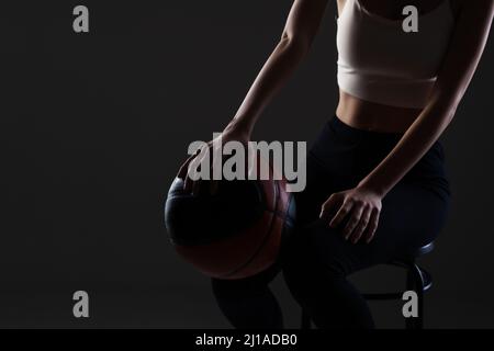 Teenage girl with basketball. Side lit studio portrait against dark background. Stock Photo