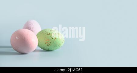 Three decorative pastel eggs on blue background. Happy Easter greeting card with copy space. Banner. Invitation. Stock Photo