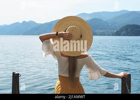 Woman is wearing straw hat looking on the beautiful lake Stock Photo