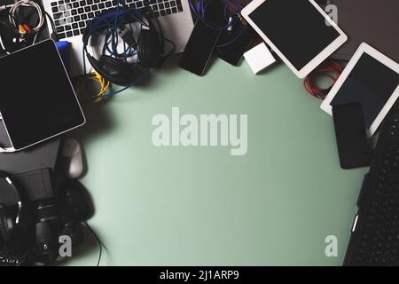 Top view to old laptop computers, digital tablets, mobile phones, many used electronic gadgets devices on green background. Planned obsolescence Stock Photo