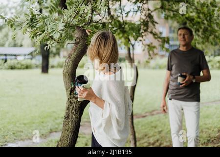 An adult mature happy couple in love hugging outdoors in city park. A blonde caucasian man and woman spend time together and drinking coffee. Senior Stock Photo