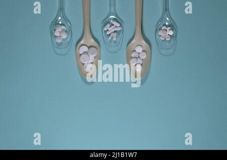 Spoons filled with various pills, on a blue background. Stock Photo