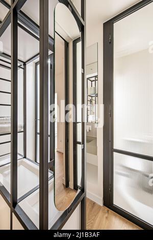 black metal shelves in bedroom with en suite bathroom with sink and mirror Stock Photo