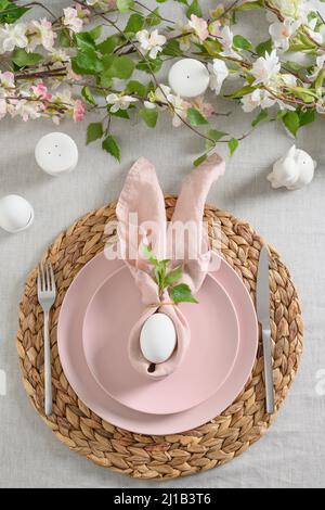 Easter dinner with white bunny, fresh spring flowers and eggs. Elegance pastel and pink tablescapes. View from above. Christian religion tradition. Ve Stock Photo
