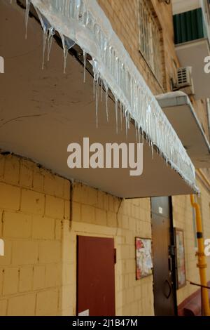 Icicles hang from front porch. Winter is in full swing, spring is coming. Icicles are dangerous. Stock Photo
