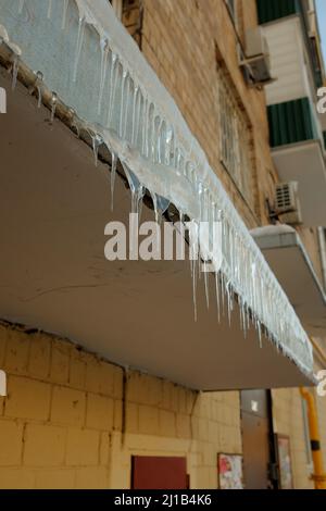 Icicles hang from front porch. Cold winter is here, spring is coming. Icicles are dangerous. Stock Photo