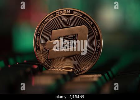 Dash cryptocurrency physical coin placed on the computer keyboard and lit with green and red lights Stock Photo