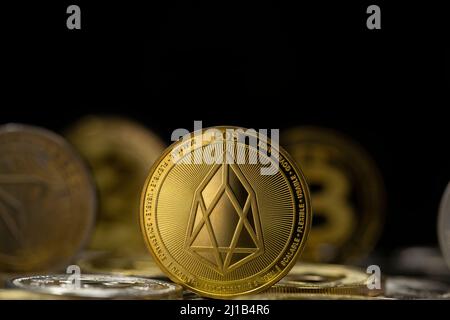 EOS cryptocurrency physical coin placed on variety of altcoins in the black background Stock Photo