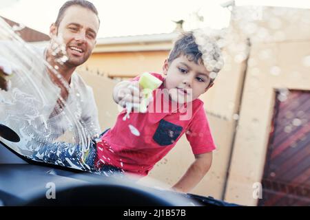 This car is going to be squeaky clean. Shot of a family washing their car in the driveway. Stock Photo