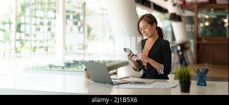 Business asian woman using mobile phone during checking an email or social media on internet. accounting financial concept. Stock Photo