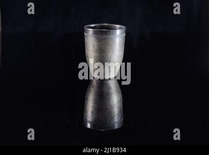 Old metal wine glass on black mirror surface Stock Photo