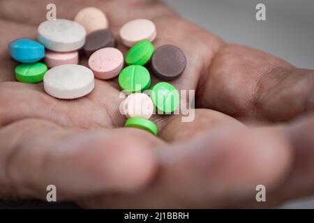 Several colored pills on the palm of the hand. Prescription drug overdose concept. Stock Photo