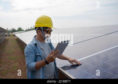 The technician uses a tablet to check the precision of solar energy to generate renewable energy. Stock Photo