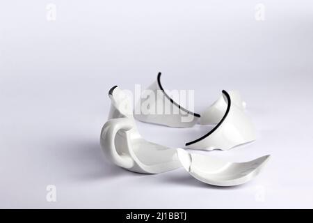 Broken white cup on white background. Concept disintegration, mockup Stock Photo