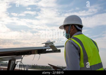 An engineer inspects a pyranometer installation in a solar farm to measure sunlight in solar power generation Stock Photo