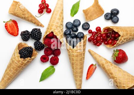 Waffle cones full of different summer berries. Ice cream cones with ripe sweet berries on white background with copy space. Summer creative concept, f Stock Photo