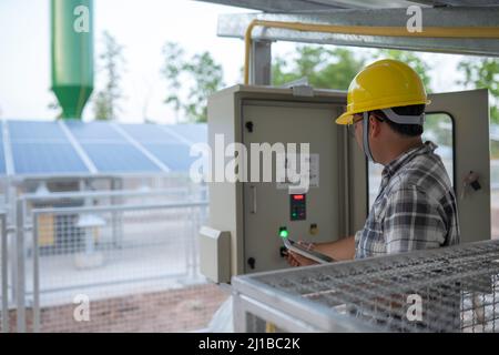 The technician at a groundwater pumping station with solar or alternative energy uses a tablet to control and monitor. Stock Photo