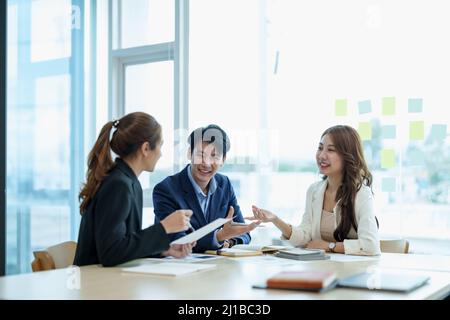 Happy group of business asian work cooperate with diverse team at office briefing, focused biracial businessman head meeting, collaborate discuss Stock Photo