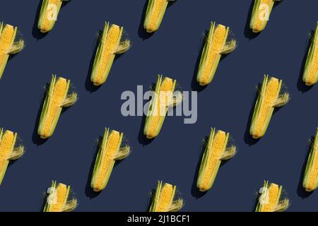 A green ear of corn. Juicy corn of a new harvest. Seamless pattern. Blue background. Stock Photo