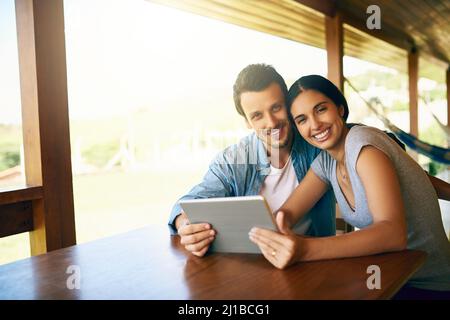 Enjoying connectivity together. Cropped shot of an attractive young married couple using a tablet together at home. Stock Photo